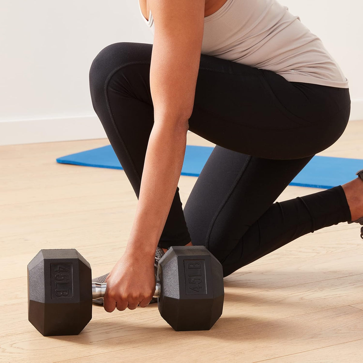 Person exercising with dumbbells on a wooden floor